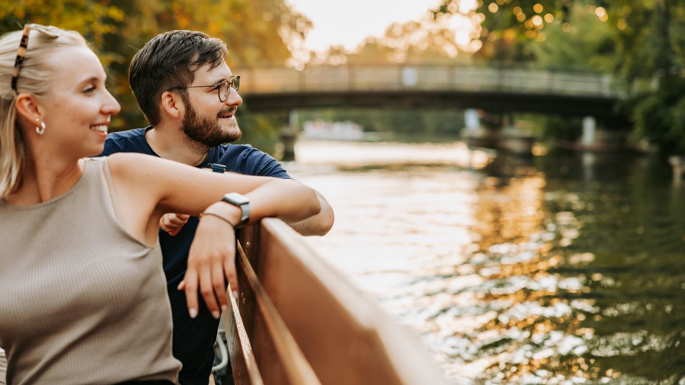 Eine junge Frau und ein junger Mann sitzen bei Sonnenuntergang auf einem Motorboot vom Stadthafen Leipzig und genießen eine Rundfahrt auf der Weißen Elster